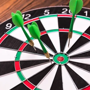 Dart board in black, white, red, & green with 3 green arrows missing the center mark.